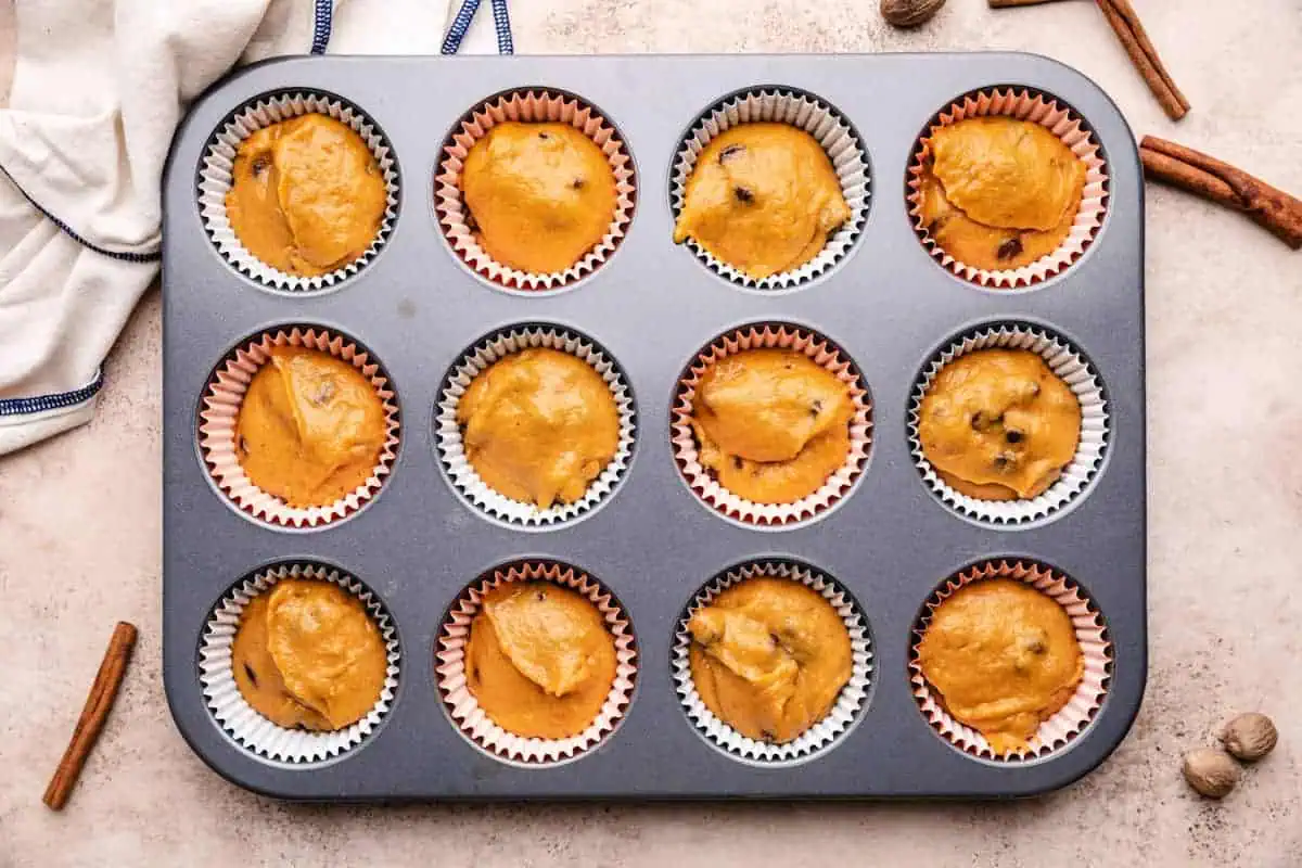 Pumpkin chocolate chip muffin batter scooped into a muffin tin.