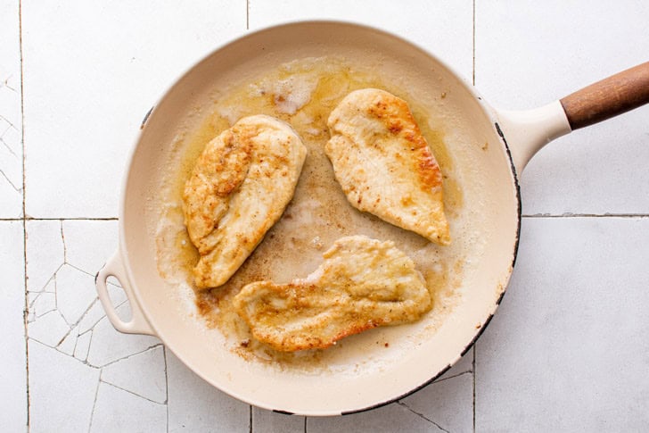 Chicken Piccata Chicken pan frying in a skillet.