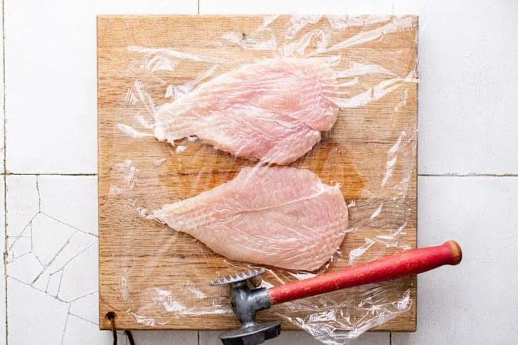 Chicken breast being pounded thin.