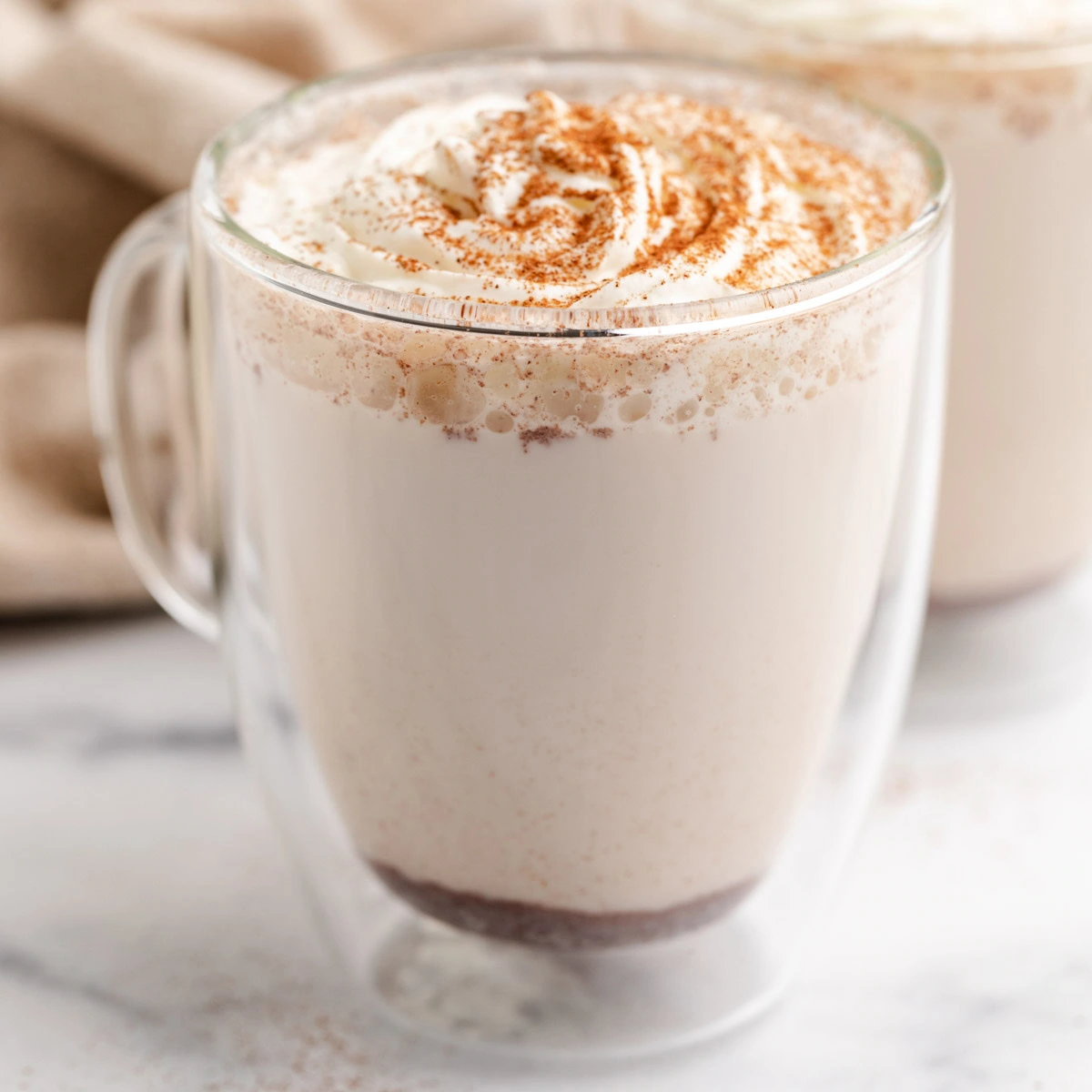 Close up view of a cinnamon maple steamer in a glass mug.