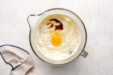 Egg and vanilla in a bowl of sweetened cream cheese.