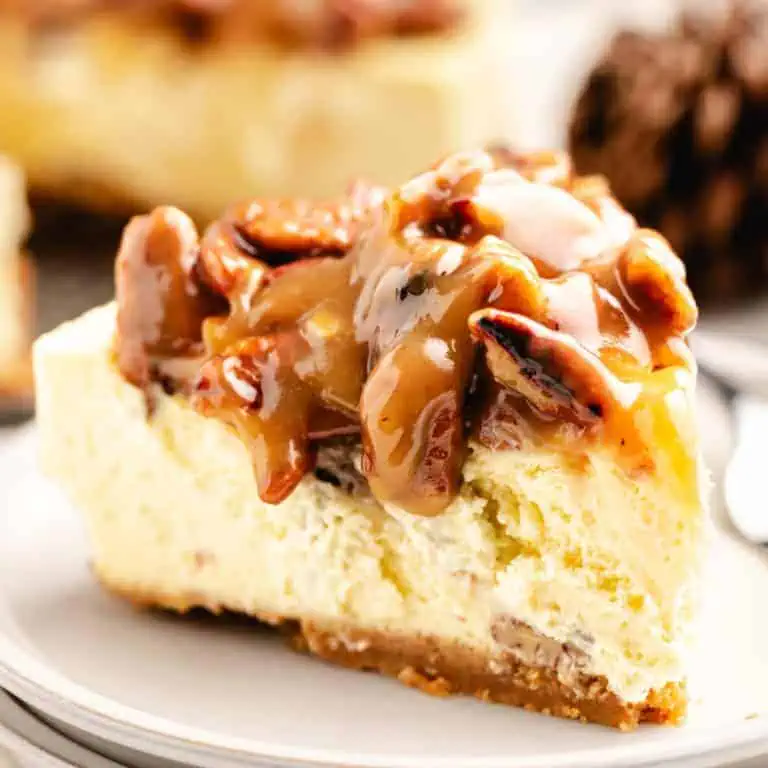 Close up view of a slice of caramel pecan pie cheesecake on white plates.