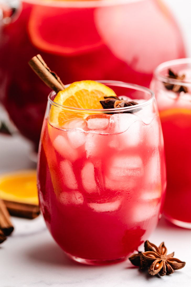 Side view of a glass of cranberry punch with spices.