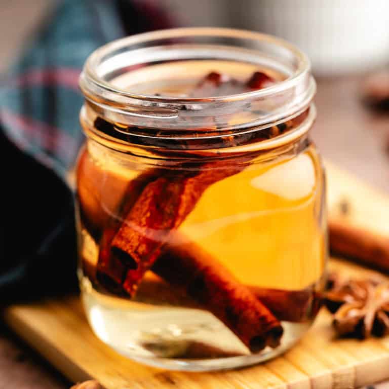 Close up view of a small jar of simple syrup with cinnamon.