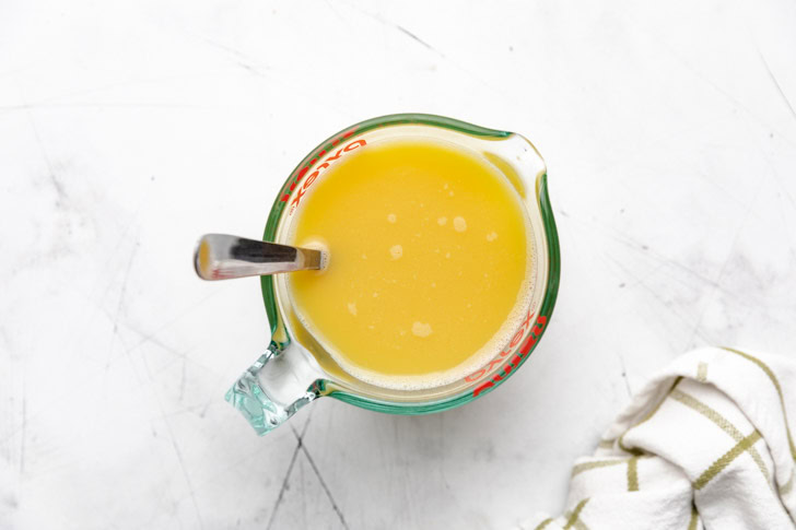 Chicken broth and eggs mixed in a measuring cup.