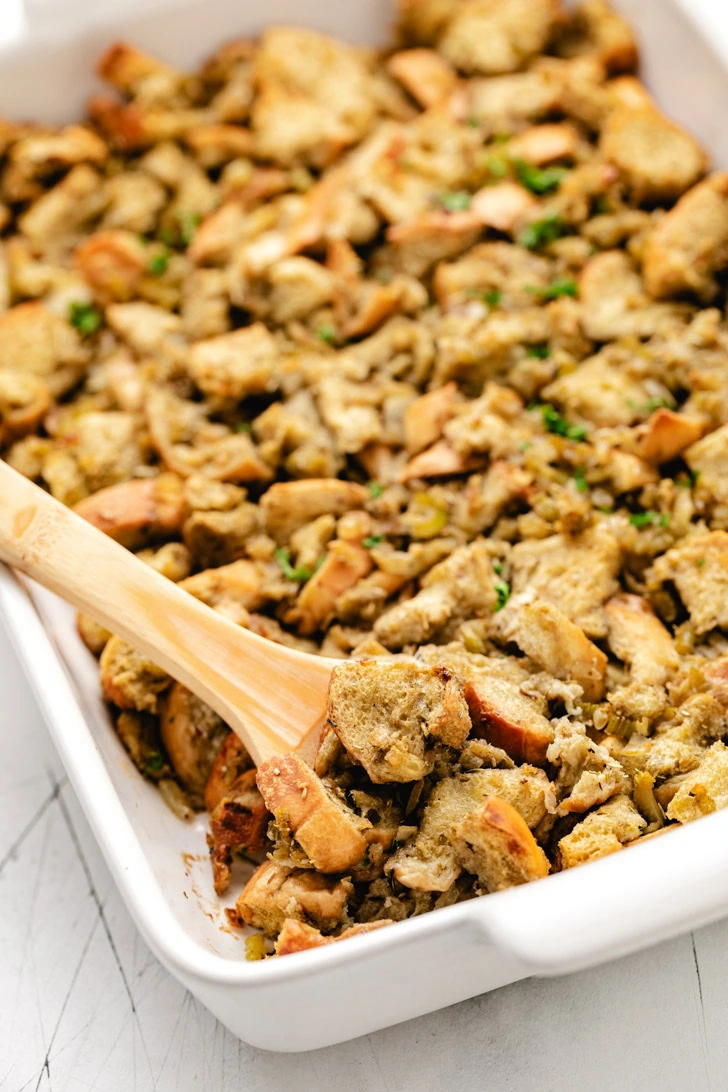 Wooden spoon scooping stuffing from a pan.