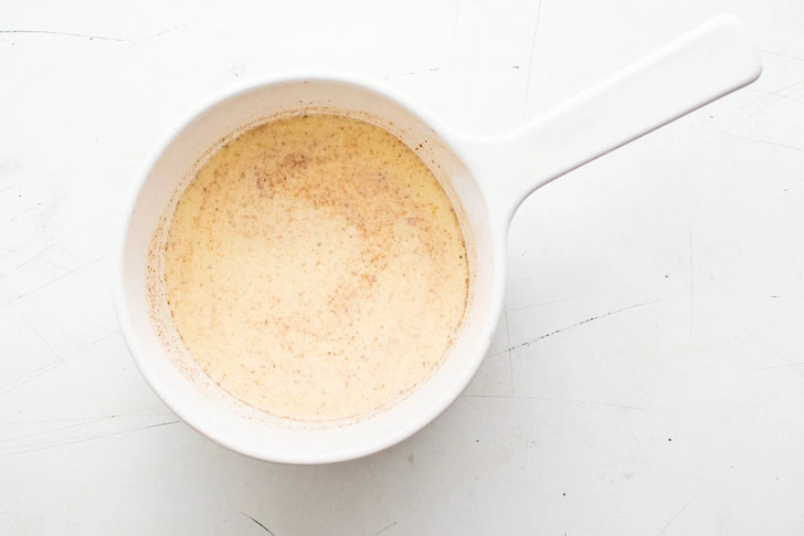 Eggnog, milk, and nutmeg in a pan.