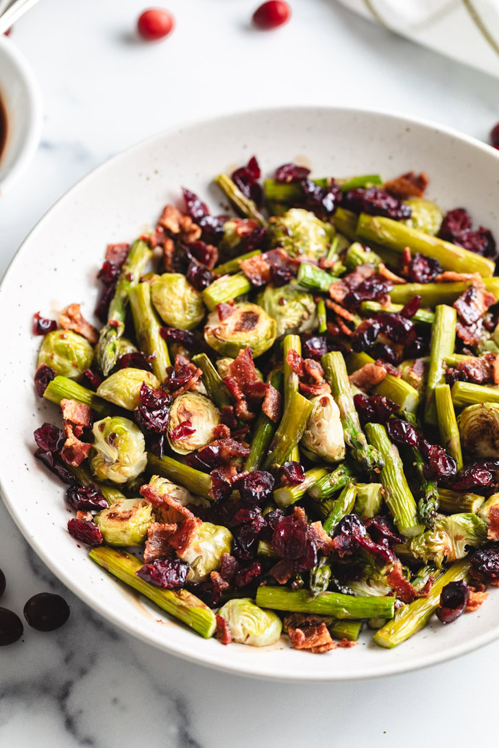 Serving dish filled with roasted veggies, cranberries and bacon.