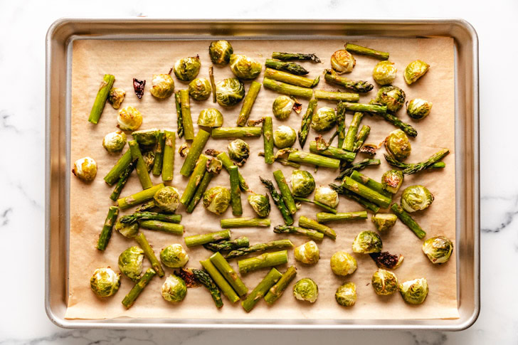 Roasted asparagus and brussels sprouts on a sheet pan.