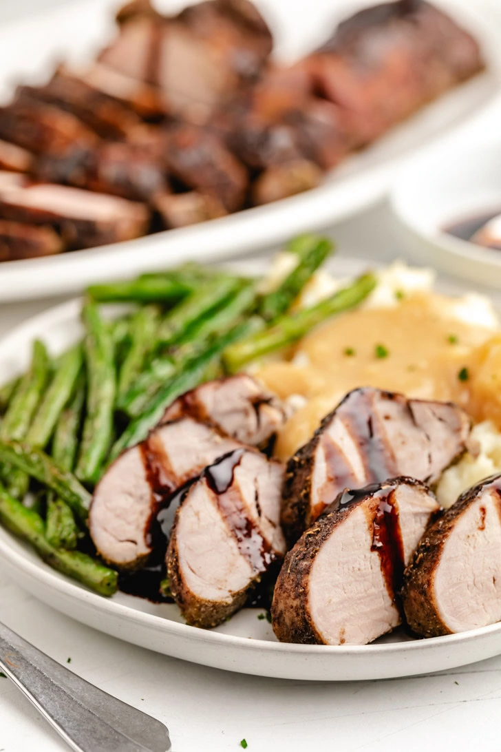 Pork medallions with glaze on a grey plate.