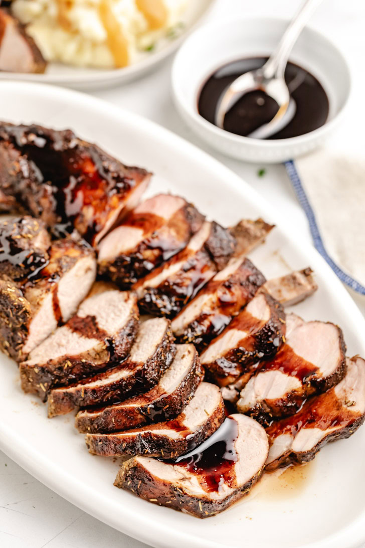 Glazed pork tenderloin on a white platter.