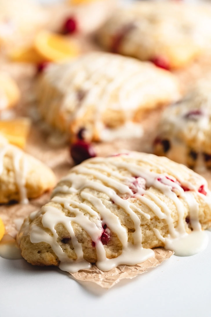 Close up view of a glazed scone on brown parchment.