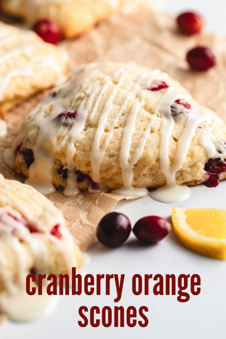 A scone with orange slices and cranberries in the background.