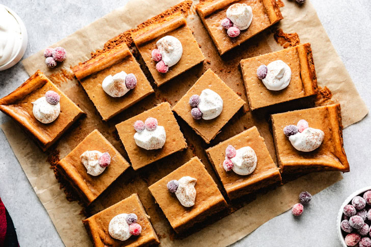 Overhead view of sliced gingerbread cheesecake bars with toppings.