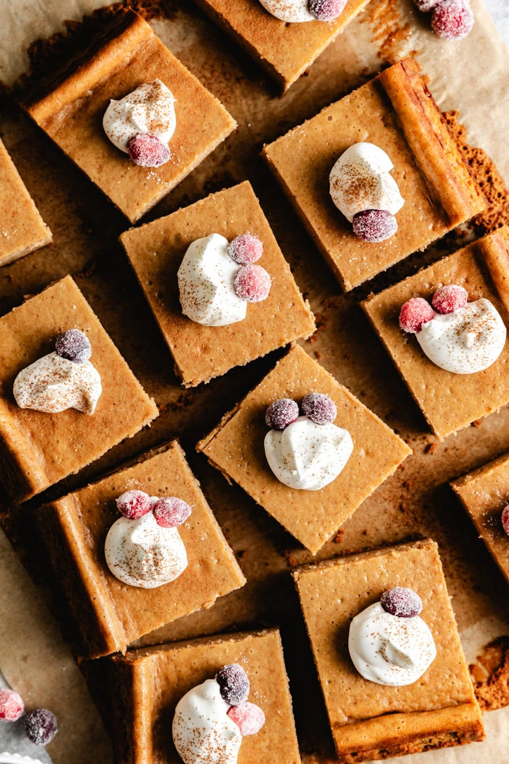 Overhead view of whipped cream and cranberries on cheesecake bars.