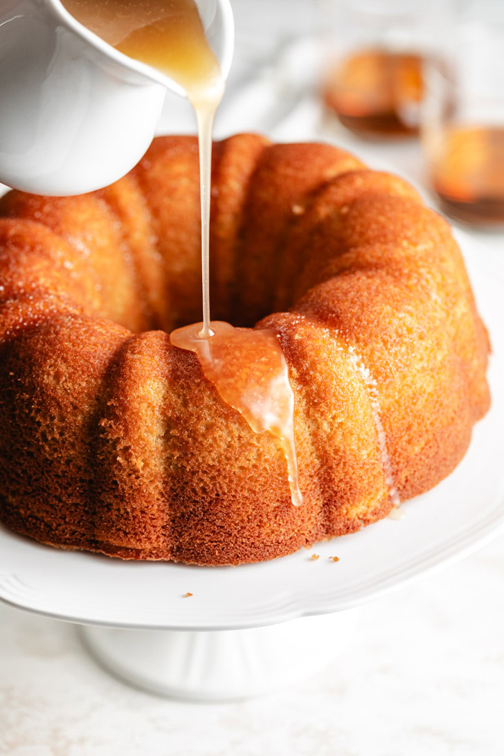 Rum syrup being poured over cake.