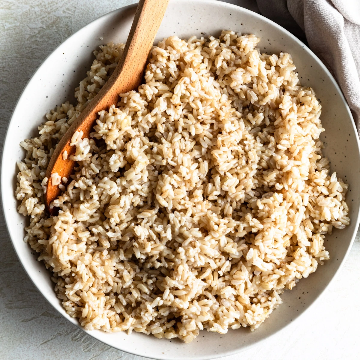 Close up view of brown rice and a spoon in a bowl.