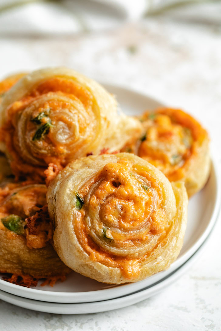 Stack of plates piled with jalapeño popper pinwheels.