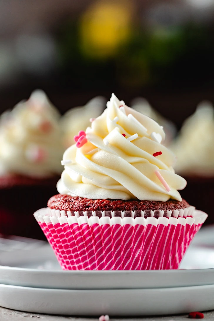 Red velvet cupcake on a stack of white plates.