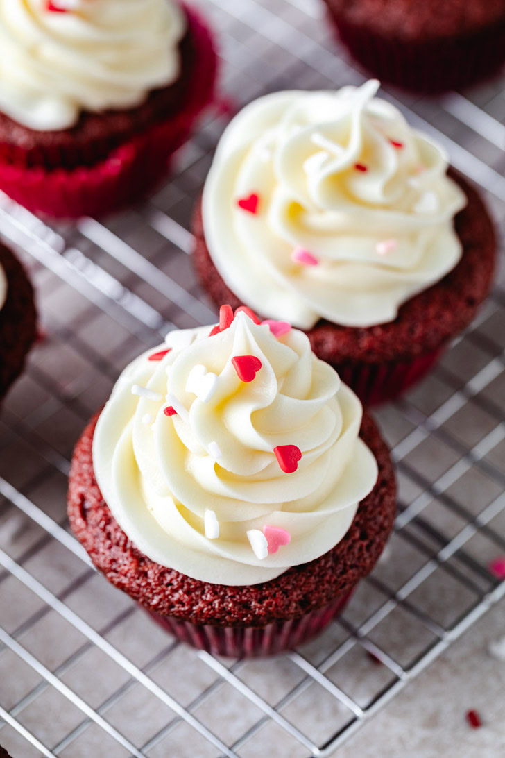 Cupcakes with sprinkles on a wire rack.