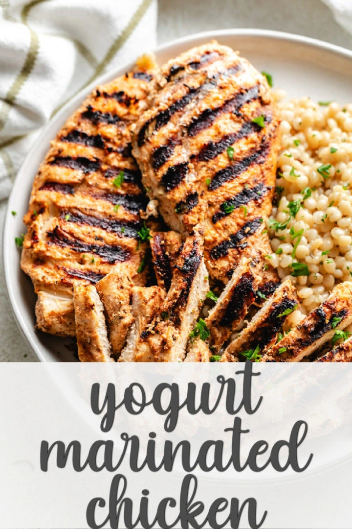 Grilled chicken breasts on a plate next to couscous.