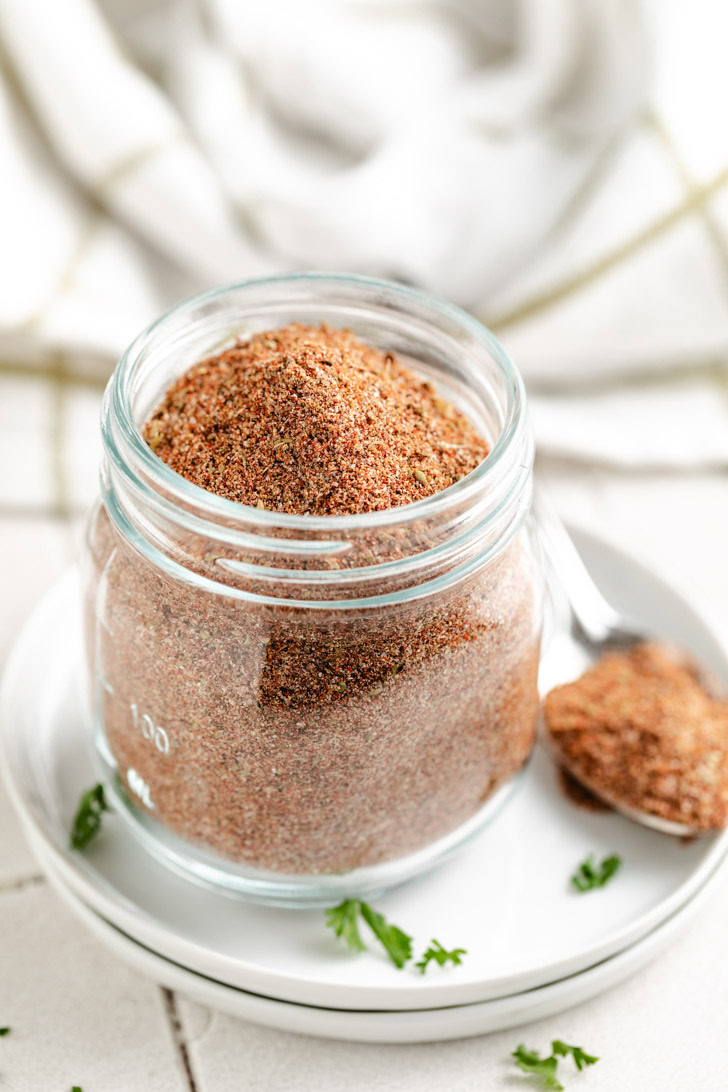 A close-up of chili seasoning in a glass jar.