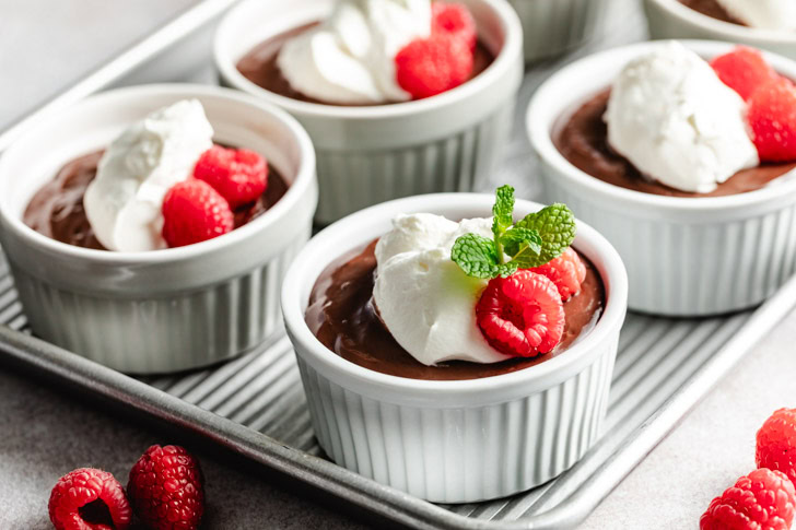 A tray of homemade pudding, topped with whipped cream and raspberries.