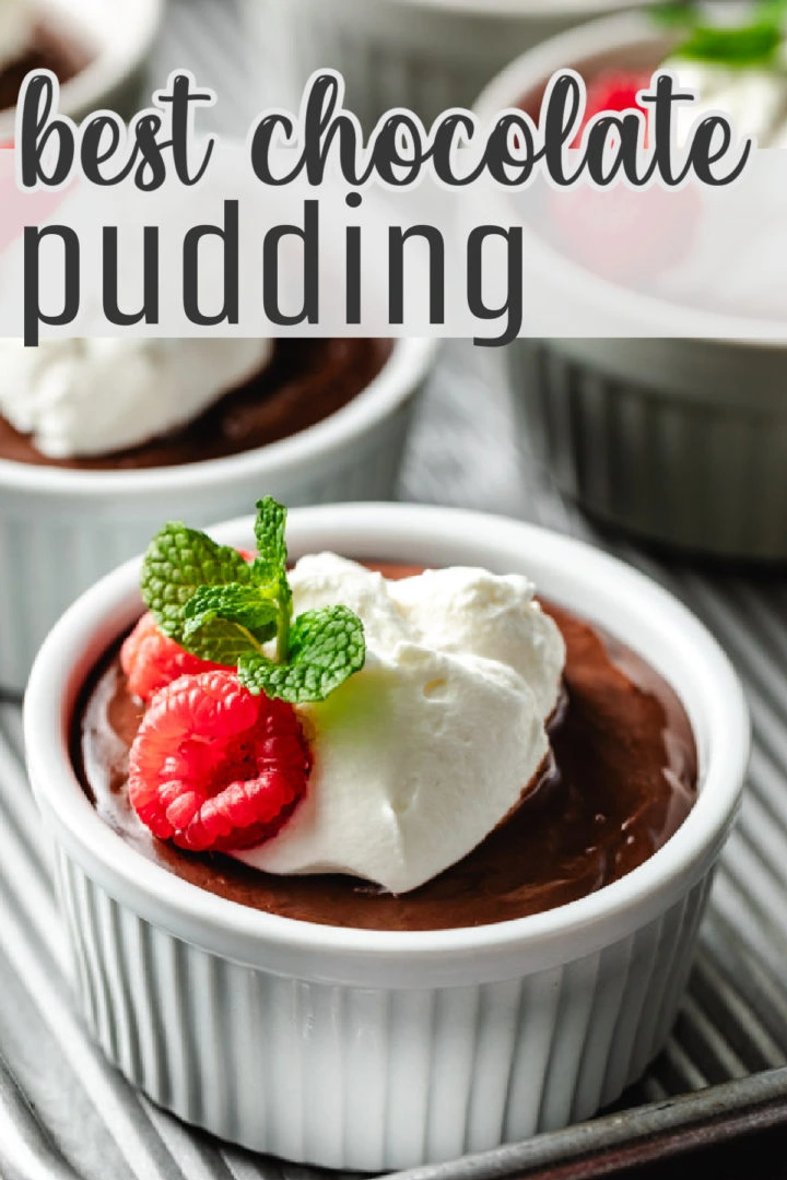 A ramekin filled with pudding, garnished with whipped cream, raspberries, and mint leaves.