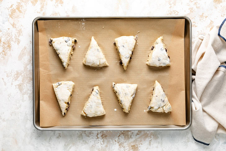 Unbaked scones arranged on a parchment-lined baking sheet.