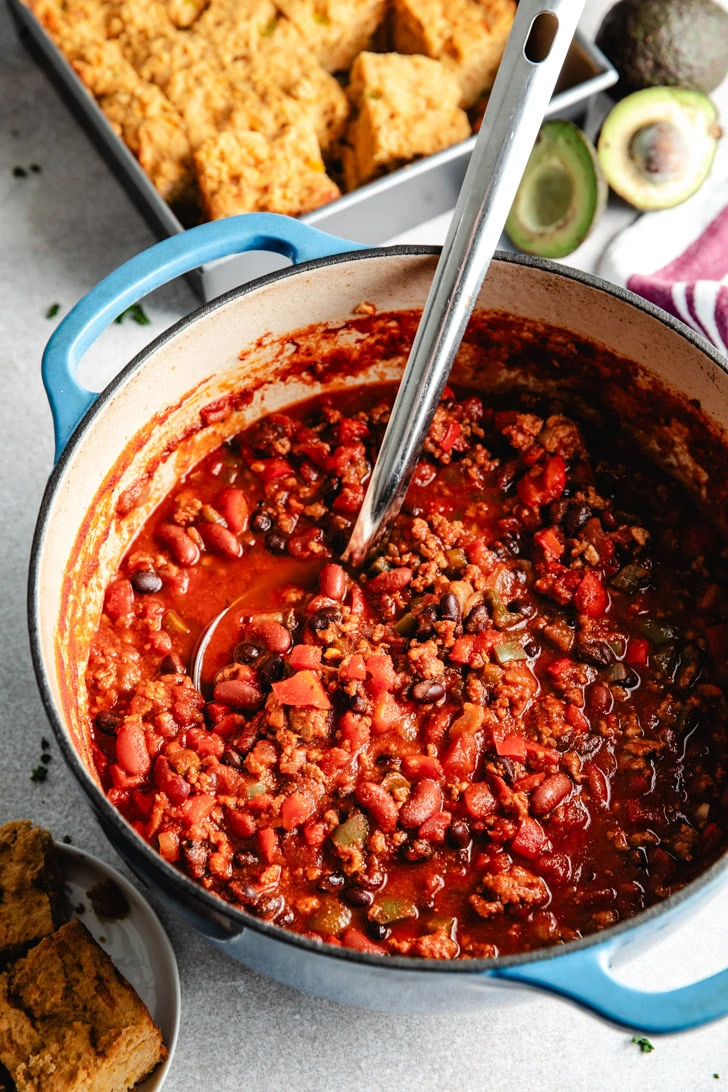 A ladle of chili being lifted from a pan.