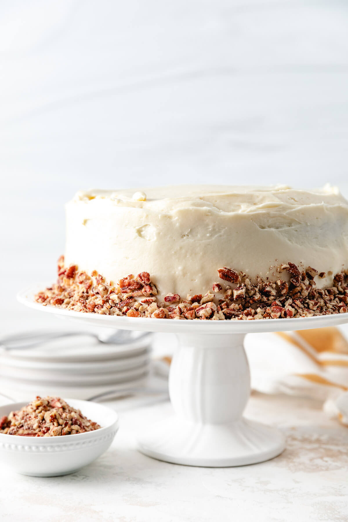 Frosted carrot cake on a cake stand.