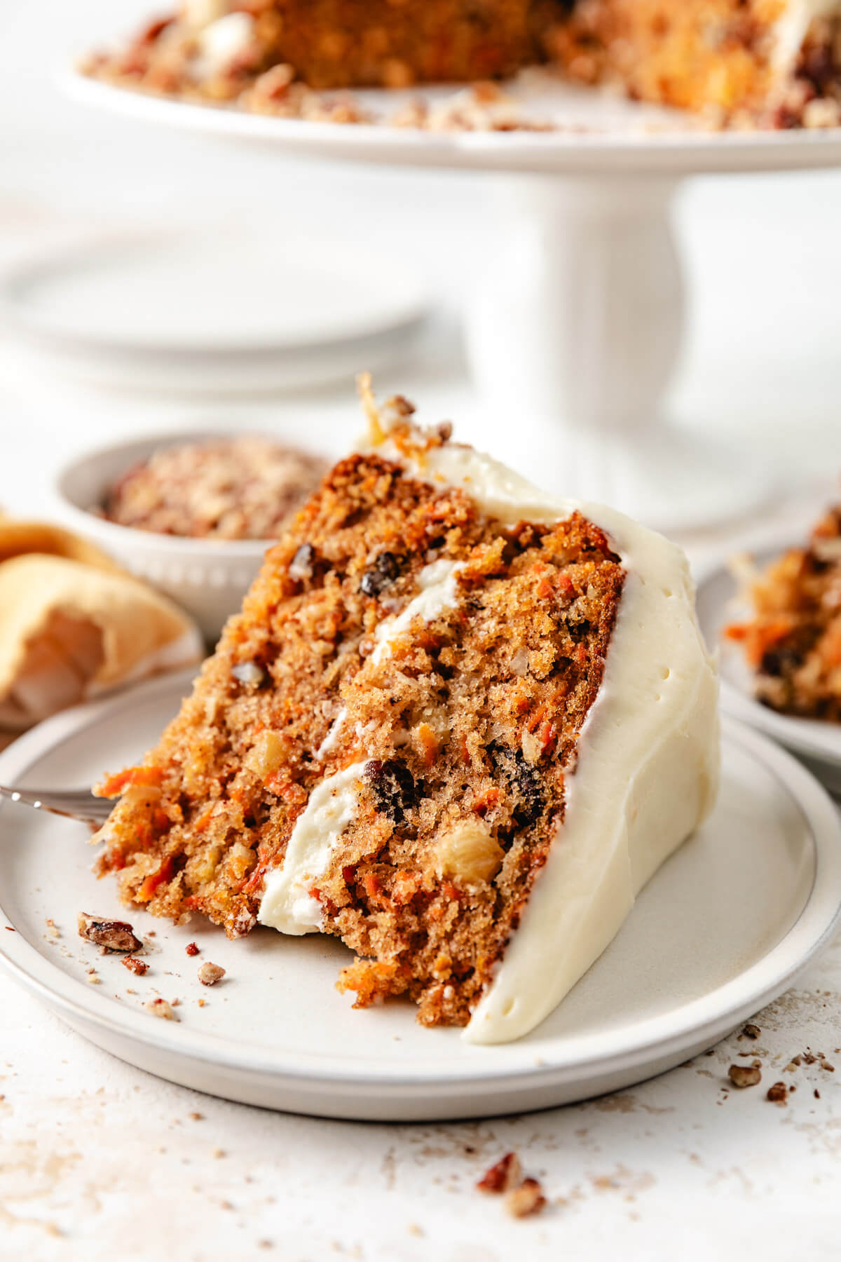 Slice of carrot cake on a plate with a fork.