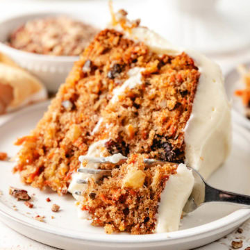 Close up view of layered carrot cake being cut with a fork.