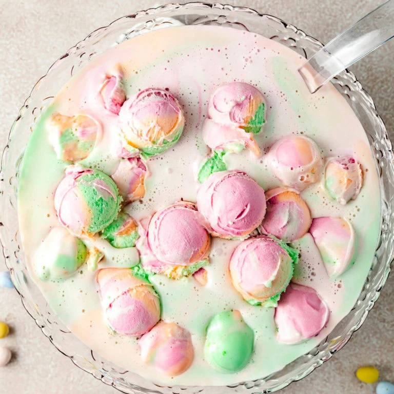 A punch bowl filled with rainbow sherbet punch.