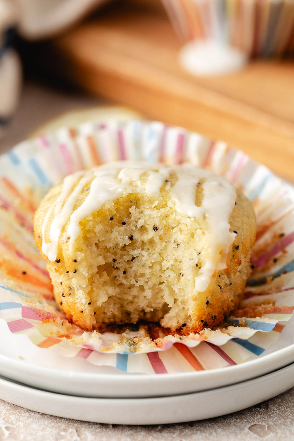 Bite taken out of a lemon muffin with poppy seeds.