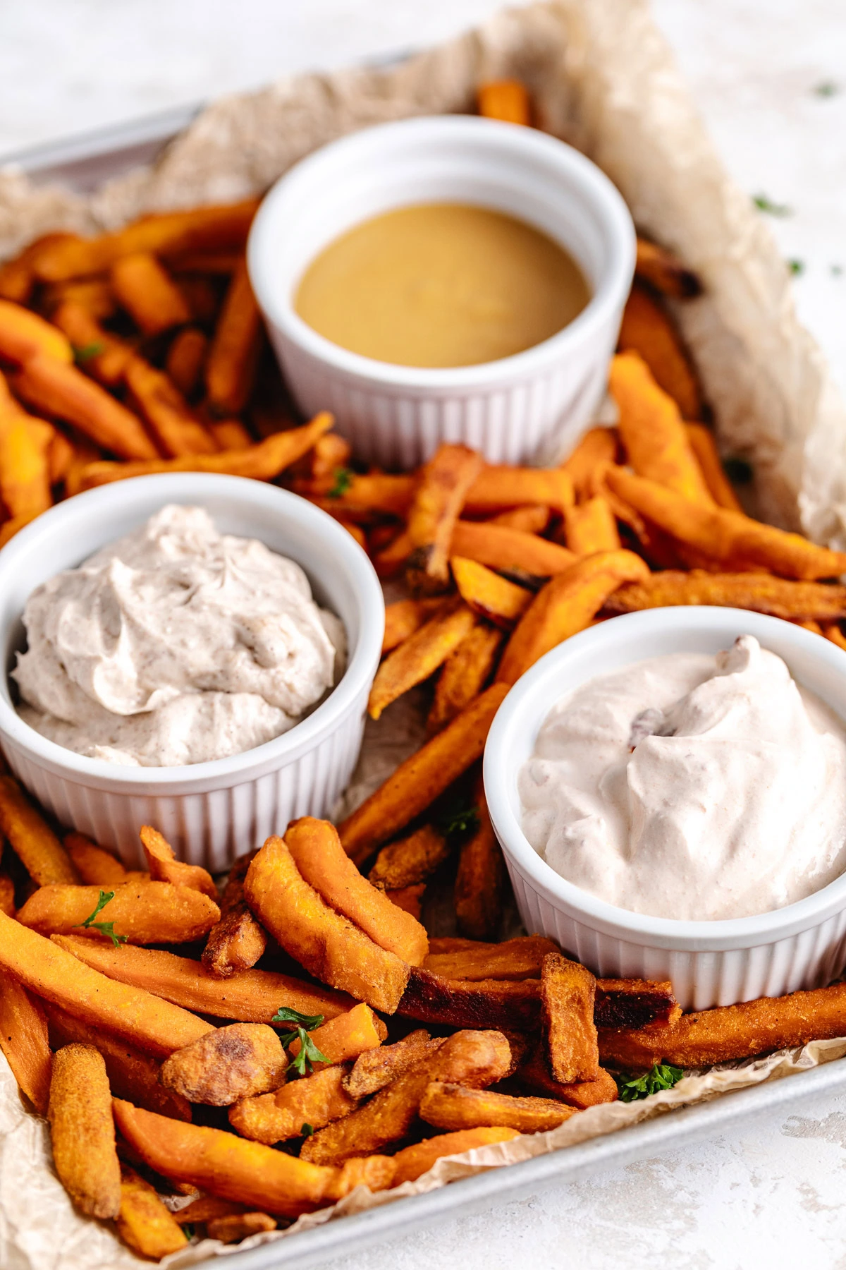 Three dipping sauces on a try with sweet potato fries.