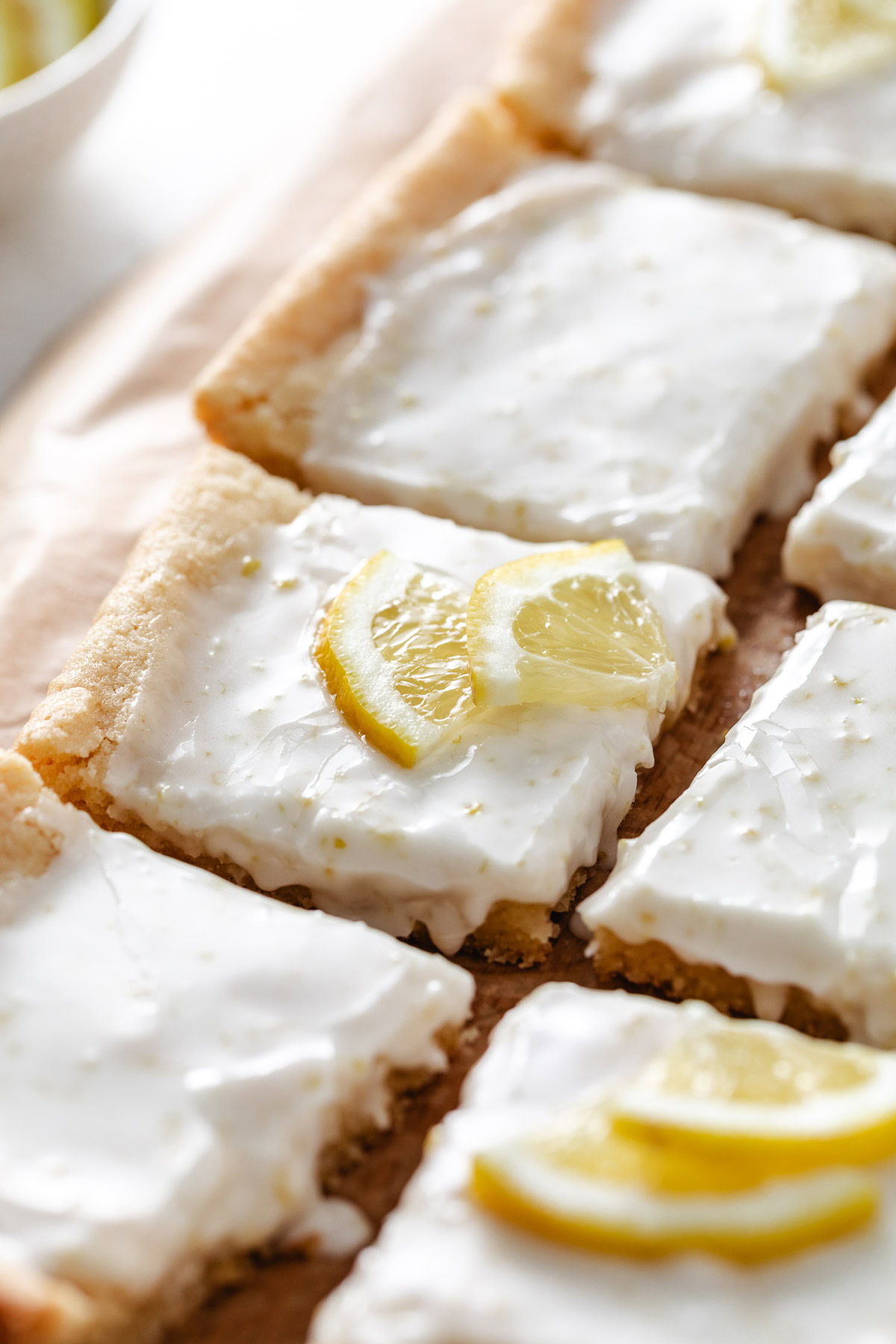Lemon bars with lemon glaze on a cutting board.
