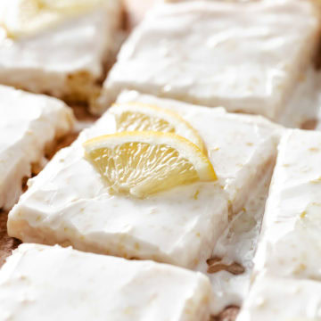 Lemon bars with white frosting and lemon slices.