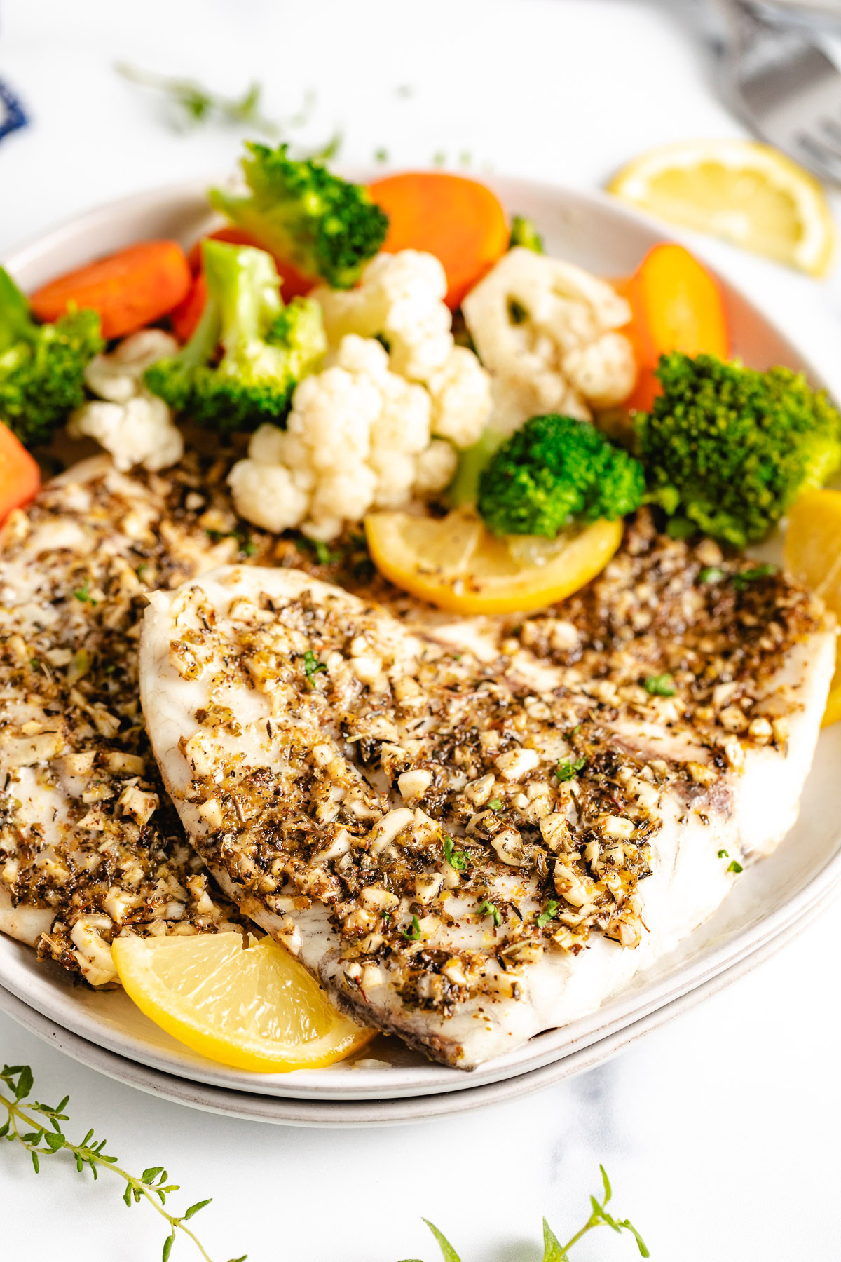 Baked fish on a plate with steamed veggies.