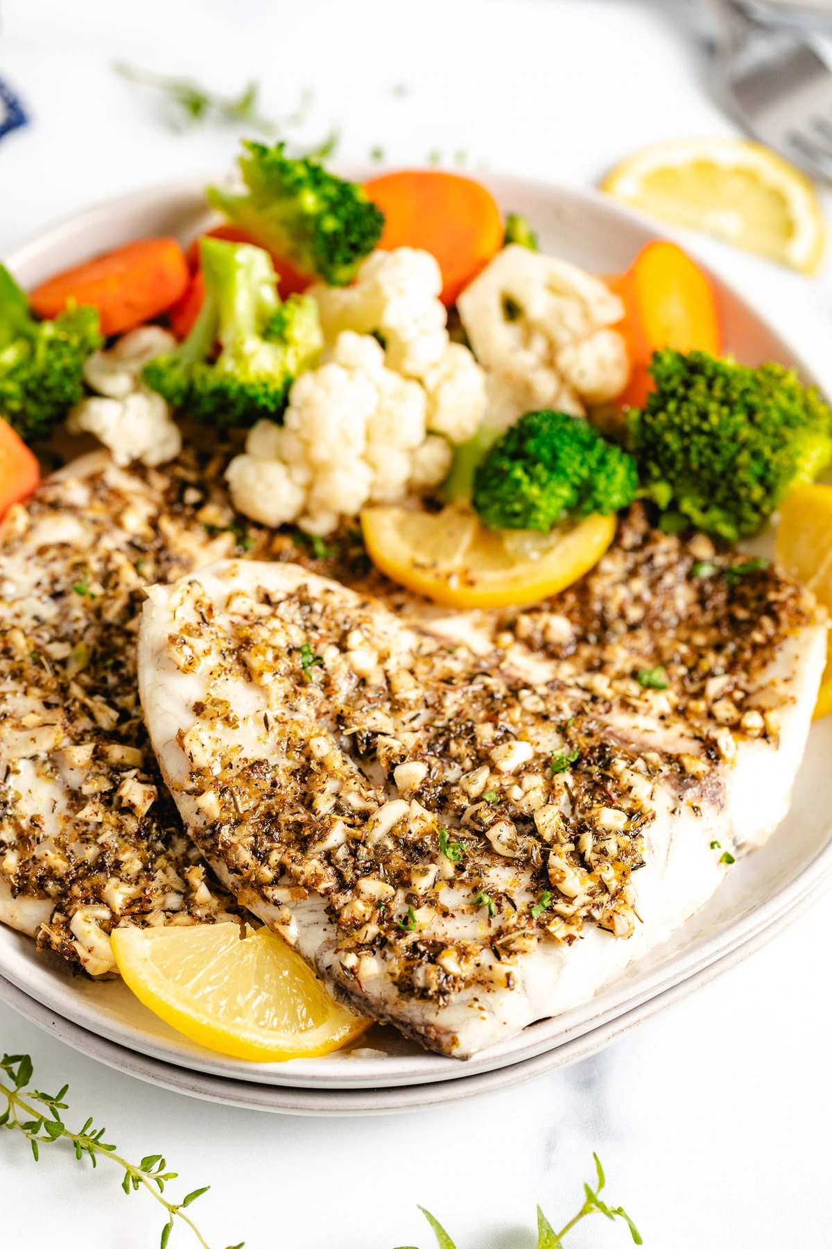 Baked fish on a plate with steamed veggies.