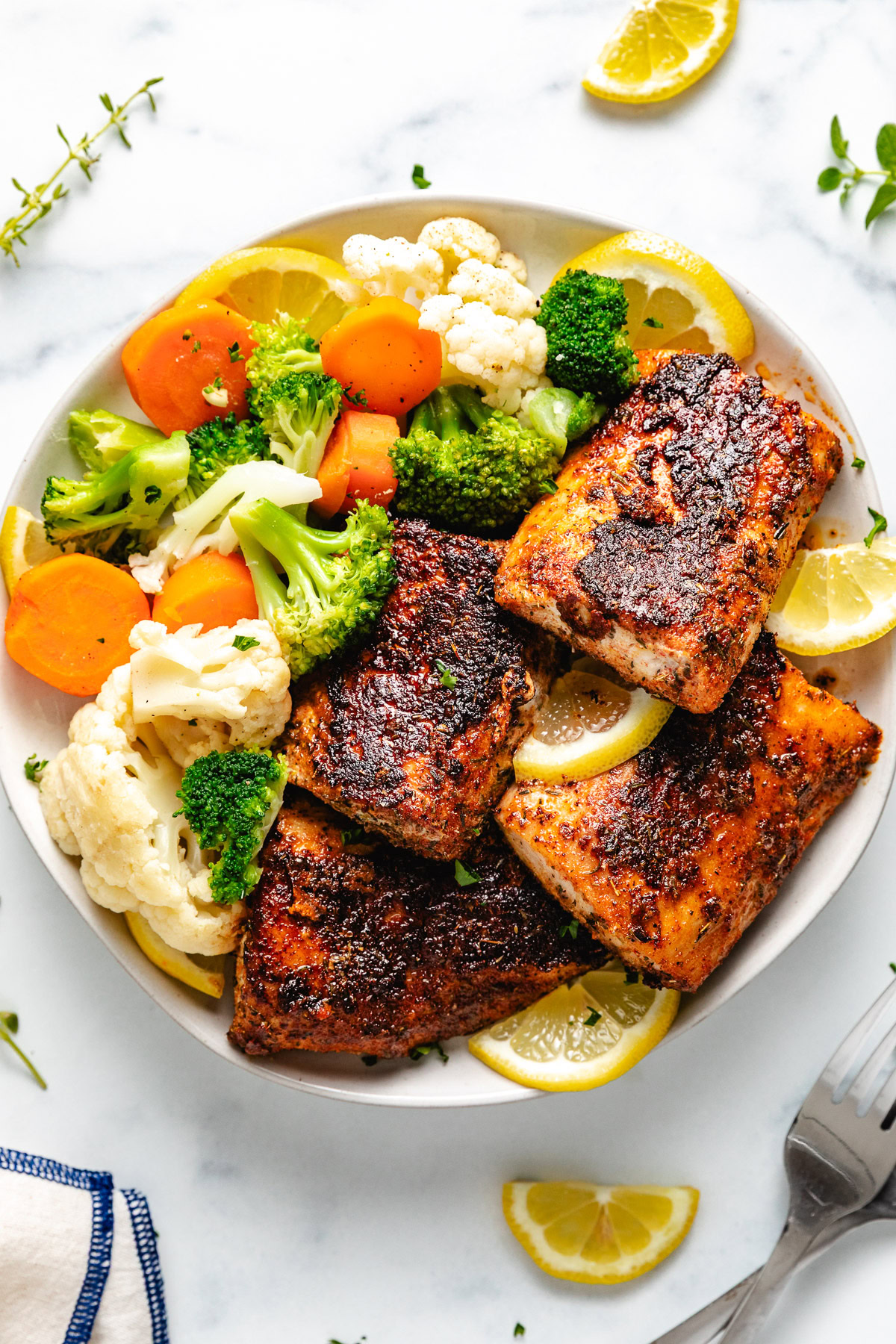 Overhead view of cajun fish with vegetables.