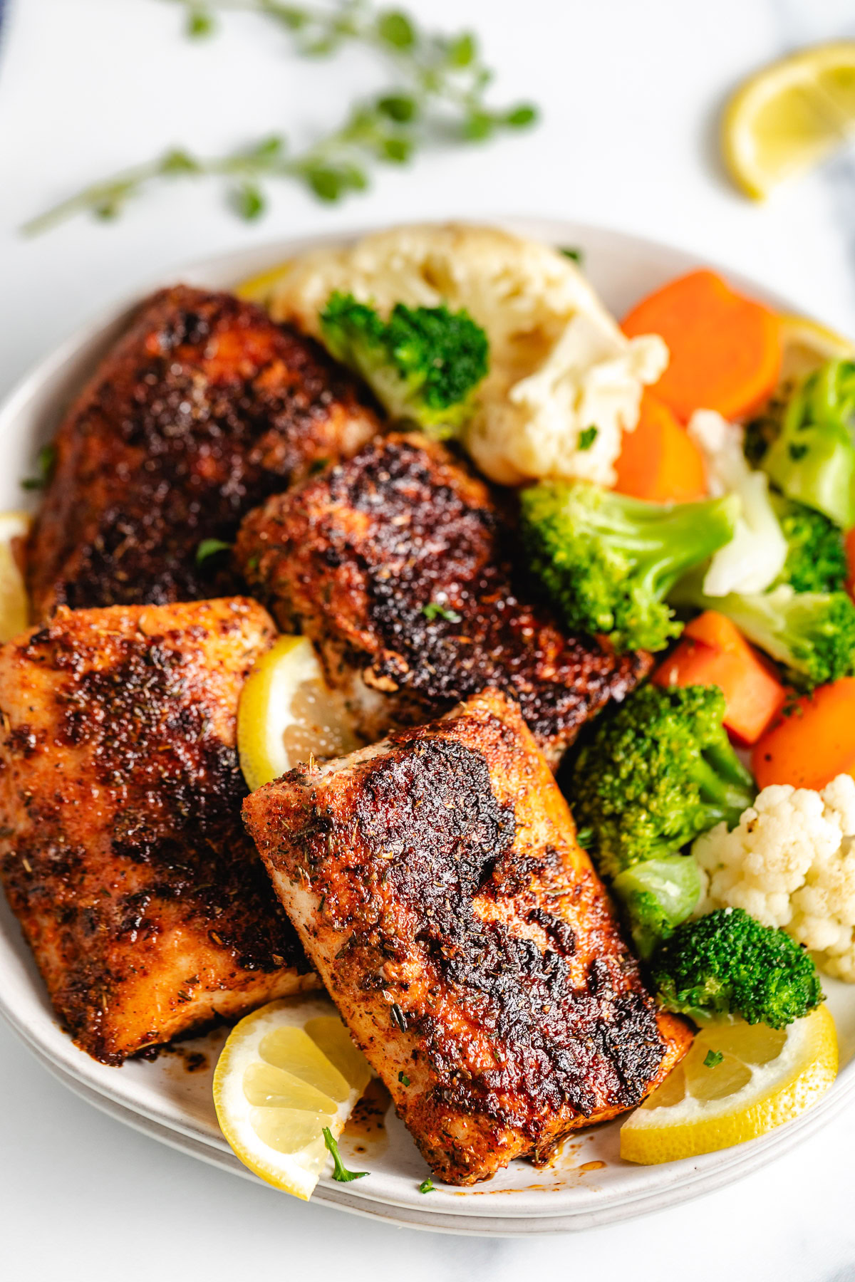 Cajun mahi mahi next to lemon slices and blanched veggies.