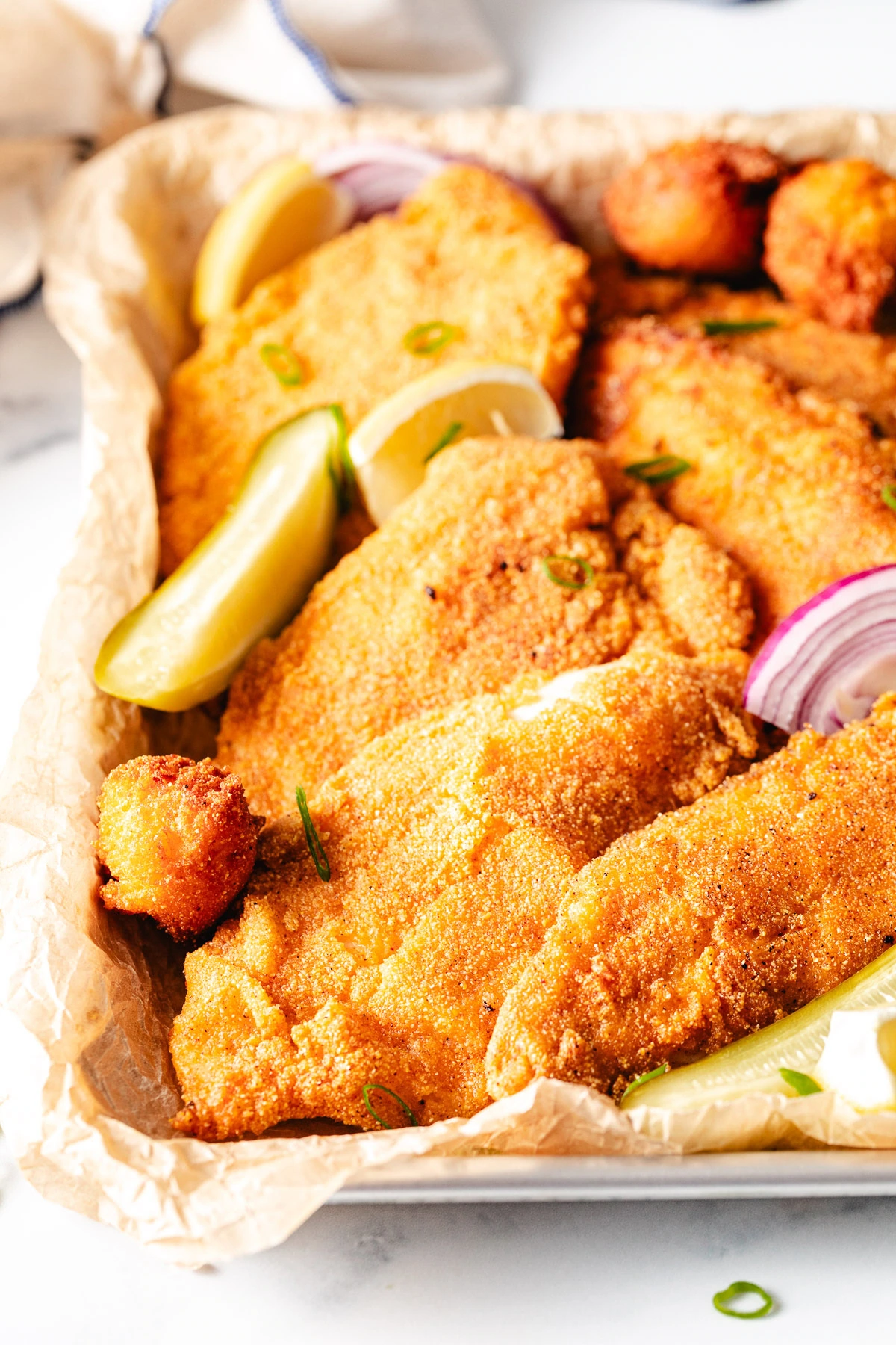 Cornmeal breaded fried catfish on a pan.