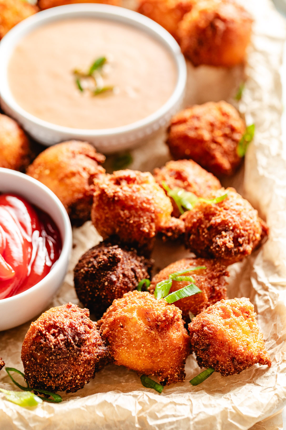 Ketchup and sauce next to a pan of hush puppies.