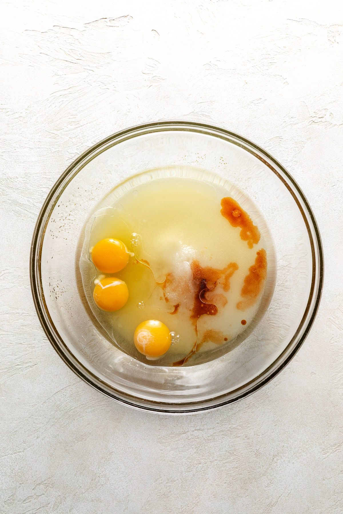 Eggs, oil, sugar, vanilla in a bowl.