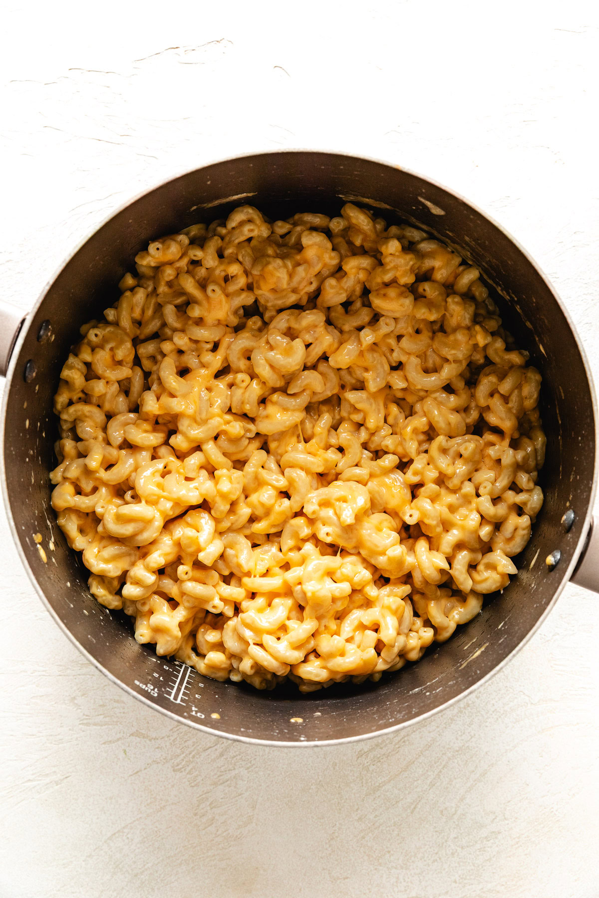 Macaroni noodles stirred with different types of cheese.