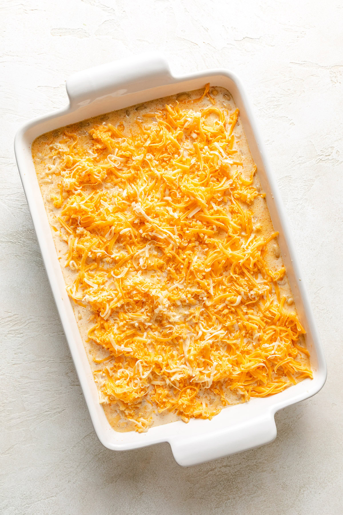Shredded cheese added to a pan of macaroni.