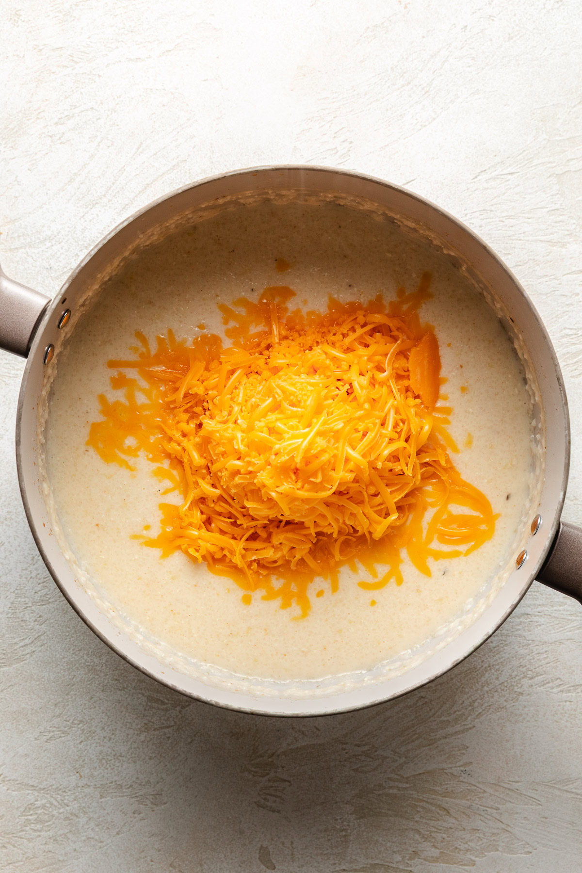 Cheese on top of grits in a pan.