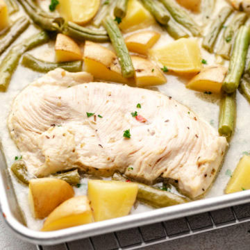 Close up view of chicken potatoes and green beans on a sheet pan.