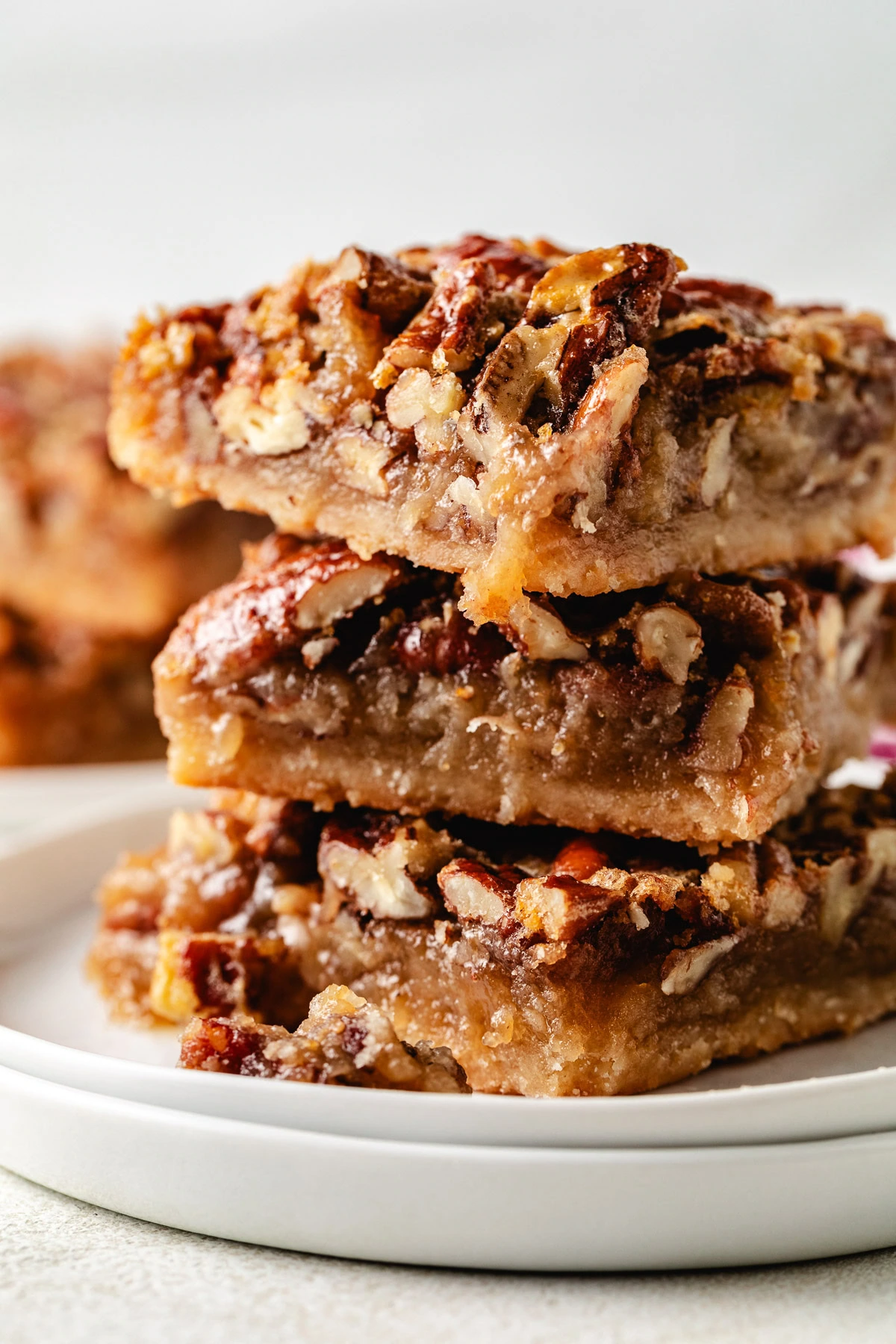 Three pecan pie bars on a set of plates.